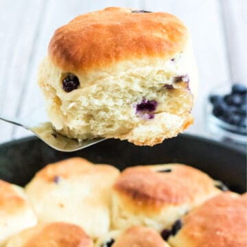 blueberry biscuit on spatula above iron skillet