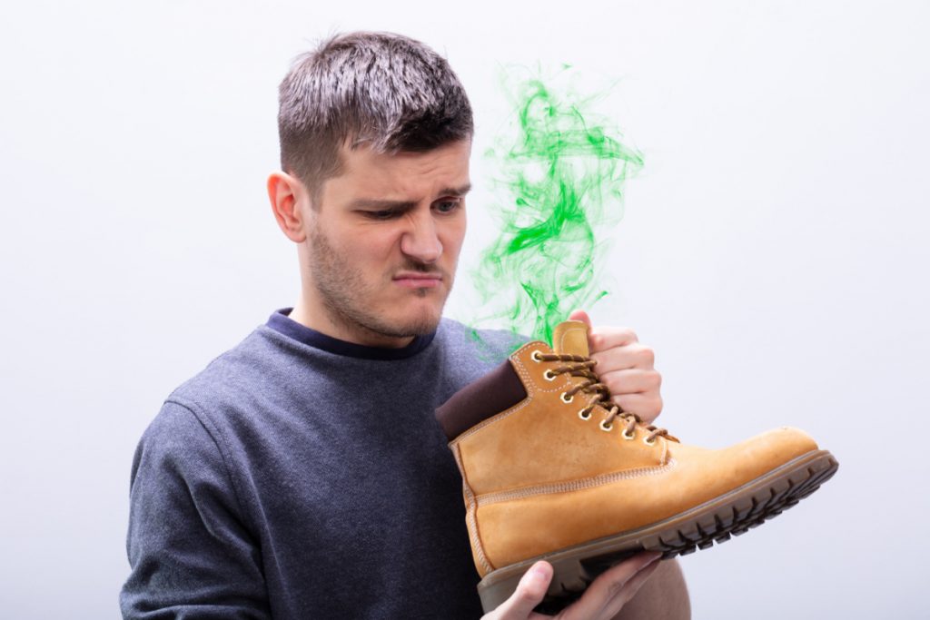 man holding stinky shoe